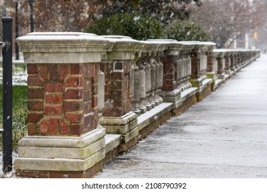 Snowy sidewalk and brick parapet fence disappearing into the distance