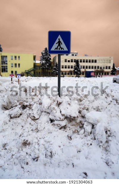 Snowy sidewalk for pedestrians with traffic sign\
after the massive\
snowfall