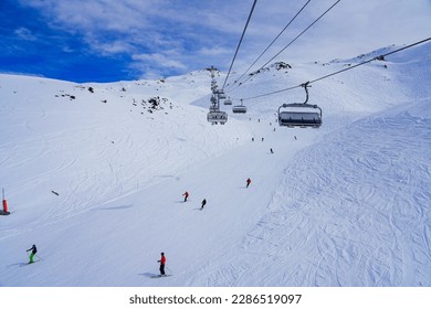 Snowy ski track in the mountains above Les Ménuires ski resort in the French Alps, as seen from a chairlift