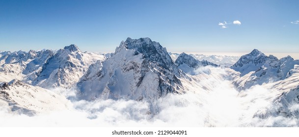 Snowy slope of high mountains above the clouds