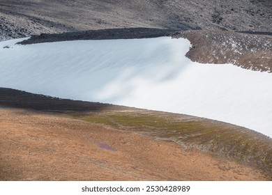 Snowy stony pass under wide big snow-white glacier in high mountains. Alpine valley and large snowfield on rocky hill slope close up. Texture of mountain terrain with water streams from glacier. - Powered by Shutterstock