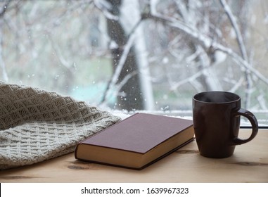 Snowy Weather. Snow On Trees And Land. Bright White Day. View Outside The Window Sill With A Cup Of Coffee And A Book. And A Warm Blanket. Wood Background.