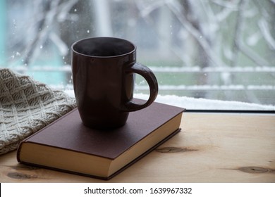 Snowy Weather. Snow On Trees And Land. Bright White Day. View Outside The Window Sill With A Cup Of Coffee And A Book. And A Warm Blanket. Wood Background.