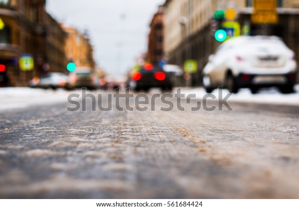 Snowy winter\
in the big city, the cars traveling on a green traffic light\
signal. Close up view from the asphalt\
level