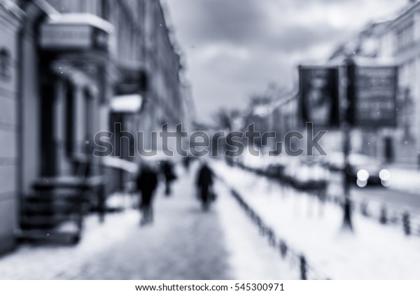 Snowy winter in the big city, the people go on
street covered with snow and billboard on the roadside. Defocused
image in the blue toning