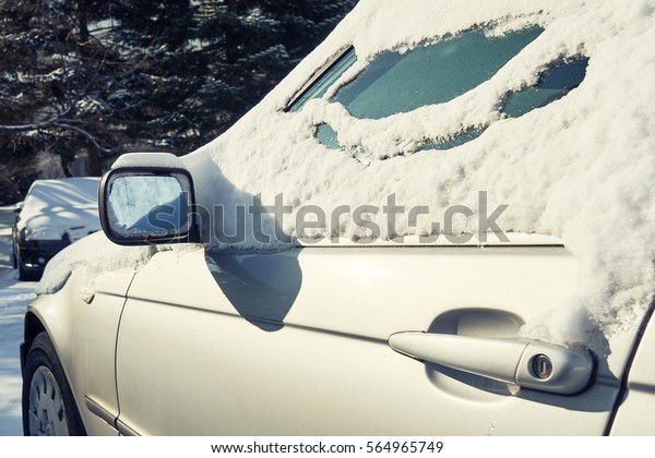 Snowy winter in a\
city on a sunny day. Car after snowfall in the parking lot\
       \
                       