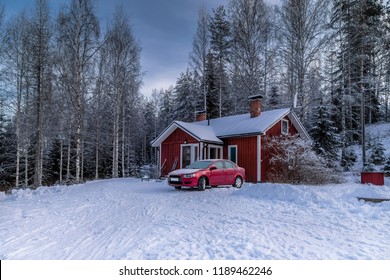 Snowy Winter Landscape With A One-story House In The Forest And A Red Car In Front Of Him