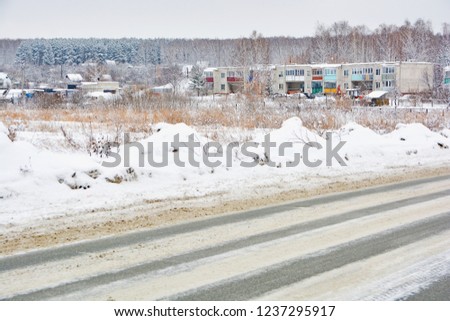 Snowy winter road in pine and birch forest.The Northern part of Russia