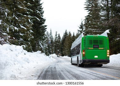 Snowy Winter Transportation Scene Of A Clean Natural Gas Bus Driving Away, On An Ice Covered Mountain Road, With Space For Text On The Left