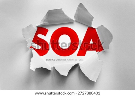SOA stands for Service Oriented Architecture, revealed behind torn paper. It is a software design style where services are provided to other components via a communication protocol over a network