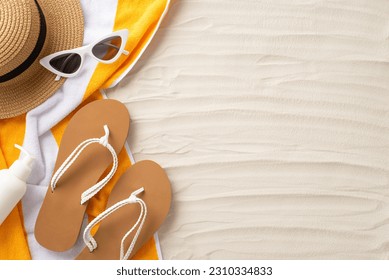 Soak up the sun's rays. Accessories laid out from top view: sunglasses, straw hat, flip-flops, sunscreen bottle, yellow towel. Sandy beach scene with an empty space for text or promotion - Powered by Shutterstock