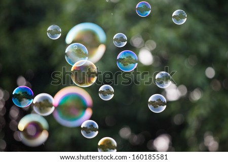 Soap -blowing in front of a green hedge.