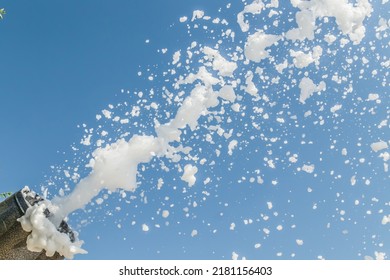 Soap foam flies from a cannon against the sky