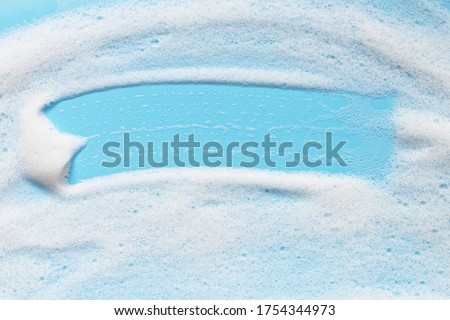 Soap foam on blue surface. Shampoo, shower gel, mousse bubbles.  Bath hygiene background. Abstract cleansing foam texture