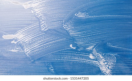 soaped window against blue sky background texture, concept for spring cleaning