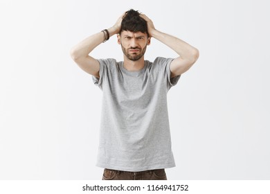 Sober Man Trying To Think, Being Troubled, Focusing On Task. Determined Good-looking Questioned Guy With Beard In Gray T-shirt, Messing Up Hair And Frowning While Having Troubled With Choice