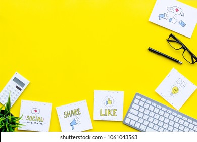 Socail Media Icons On Work Desk Of Marketing Expert. Digital Promotion Of Goods And Services. Yellow Background Top View Copy Space