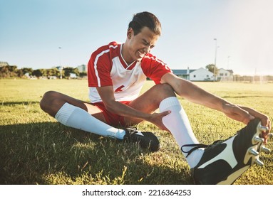 Soccer, athlete and injury on sport field while exercise, workout and practice suffer on game day. Football, health and painful leg from training, sore or muscle for stretching, fallen or foot pain - Powered by Shutterstock