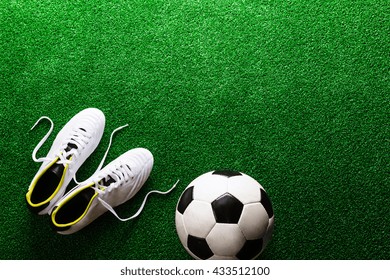 Soccer ball and cleats against green artificial turf, studio sho - Powered by Shutterstock