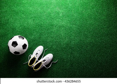 Soccer ball and cleats against green artificial turf, studio sho - Powered by Shutterstock