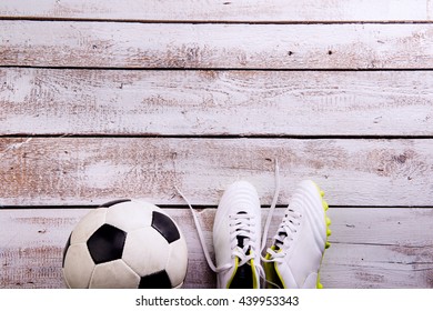 Soccer Ball, Cleats On White Wooden Floor, Studio Shot