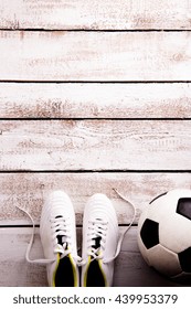 Soccer Ball, Cleats On White Wooden Floor, Studio Shot