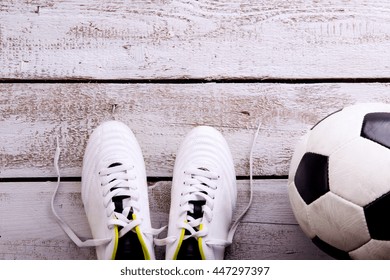 Soccer Ball, Cleats On White Wooden Floor, Studio Shot