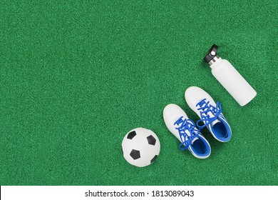 Soccer ball, cleats and water bottle on green artificial turf, top view with copy space, football concept. Game or sports club class and tournament concept - Powered by Shutterstock