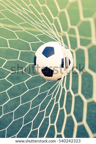 soccer ball in goal net with green grass - retro vintage filter effect