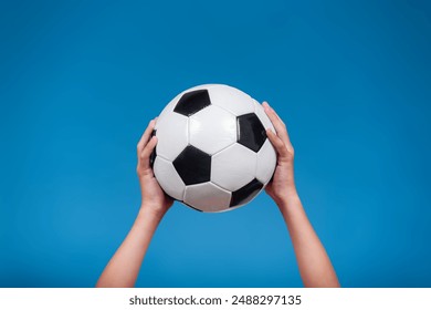 Soccer ball held by hands of a kid isolated on blue background. Concept of sports.  - Powered by Shutterstock