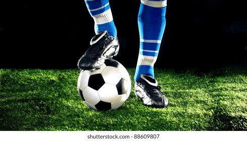 Soccer Ball With His Feet On The Football Field