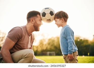 Soccer ball, holding it by heads, fun. Happy father with son are on the field at summertime. - Powered by Shutterstock