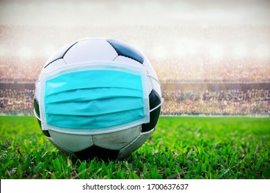 Soccer Ball With Medical Mask In The Stadium. All Event Of Soccer Pause Break. Covid-19 Spreading Outbreak