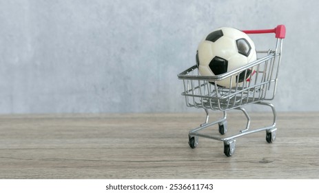 Soccer Ball in Mini Shopping Cart on Wooden Surface with Gray Background - Powered by Shutterstock