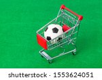 Soccer ball in shopping cart on green foorbal field