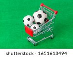 Soccer balls in shopping cart on green foorbal field