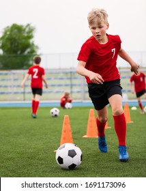 Soccer Boy On Training With Ball And Soccer Cones. Dribbling Drill. Soccer Kids Dribble Training. Youth Soccer Club Practice Session. Boys In Sports Team In Red Jersey Uniforms