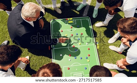 Soccer coach explains strategy using a tactical board with players gathered around