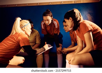 Soccer Coach And Her Female Team Analyzing Game Plan Before The Match In Locker Room.