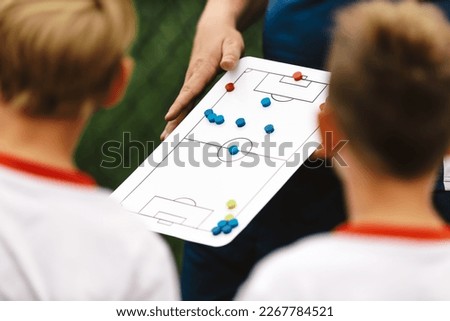 Soccer Coach Holding Tactics Board Football Tactics Board Strategy in Soccer. Coaching Kids Soccer. Football Team with Coach at the Stadium
