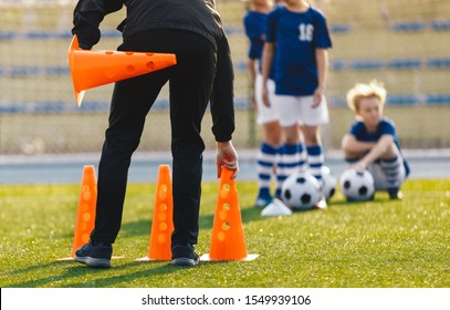 Soccer Coach Placing Training Cones For Kids Sports Team. Children On Soccer Football Class. Physical Education Soccer Unit Practice On Summer Sunny Day