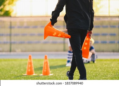 Soccer Coach Preparing Training Field. Trainer Holding Soccer Practice Cones. Coaching Youth Sports Team. Football Stadium in the Blurred Background - Powered by Shutterstock