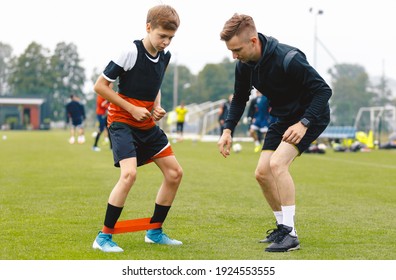 Soccer Coach With Young Player. Boy on Football Field Stretching on Exercise Mat. Male Coach and Personal Trainer Giving Advices to Young Athlete - Powered by Shutterstock