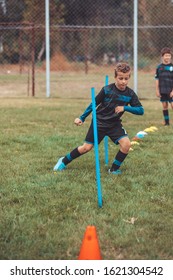 Soccer Drills: The Slalom Drill. Youth Soccer Practice Drills. Young Football Player Training On Pitch . Soccer Slalom Cone Drill. Boy In Soccer Jersey Running Between Cones And Ring Ladder Marker.