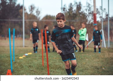 Soccer Drills: The Slalom Drill. Youth Soccer Practice Drills. Young Football Player Training On Pitch . Soccer Slalom Cone Drill. Boy In Soccer Jersey Running Between Cones And Ring Ladder Marker.
