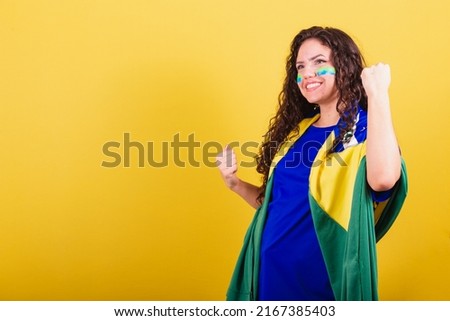 Soccer fan woman, brazil fan, closed fists, celebrating, cheering for a goal.