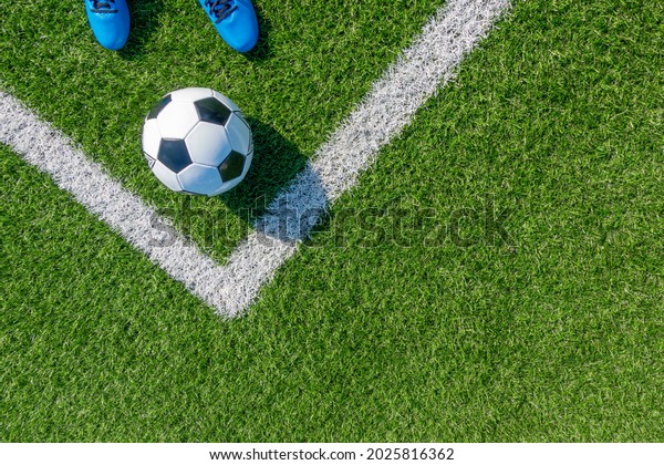 Soccer football background. Soccer ball and pair of\
football sports shoes on artificial turf soccer field with white\
line. Top view