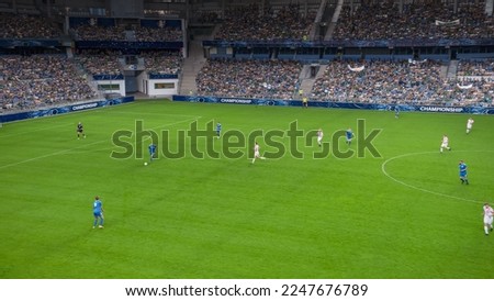 Soccer Football Championship Stadium with Crowd of Fans: Blue Team Forward Attacks, Dribbles, Players Defending The Goals, Ready To Counterattack. Sport Channel Broadcast Television. High Angle Wide.