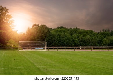 Soccer of football field with freshly cut grass at sunset. Sport training ground with goal posts. Nobody. Dramatic sunset sky. - Shutterstock ID 2202554453