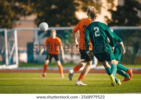 Soccer football players kick a ball towards a goal during a match in the soccer stadium. Youth football teams in a game. Footballers in action on the tournament game. Adult football competition